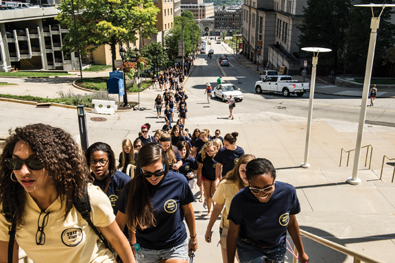 A steady stream of students walk up DeSoto Street toward the Petersen for convocation.