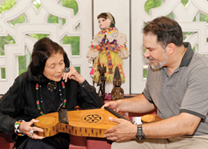 E. Maxine Bruhns, director of the Nationality Rooms and Intercultural Exchange Programs, and Michael Walter, Nationality Rooms tour coordinator, examine a wooden Lithuanian kankles, a string musical instrument in the zither family. It is believed to have been donated to Pitt in 1942. Below, a Chinese bronze lion and a Jablonica Slovak doll. (Photo by Emily O'Donnell)