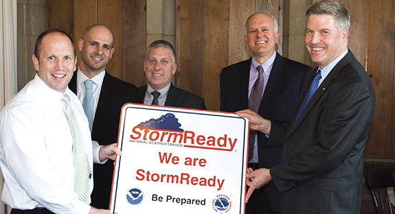 April sunshine streamed into Chancellor Patrick Gallagher’s office recently when a National Weather Service representative visited, declaring the University to be a StormReady institution. The distinction means that Pitt has demonstrated its commitment to the safety of its students, staff, and faculty in the event of severe weather. “Pitt administrators spent time and effort to attain this recognition,” said Fred McMullen, Warning Coordination Meteorologist for the National Weather Service. University officials participated in a SKYWARN session to train severe-weather spotters and have also developed a hazardous weather plan, he added. From left, McMullen, and Pitt officials Chris Casamento, regional health and safety coordinator, Department of Environmental Health and Safety; Ted Fritz, associate vice chancellor, Department of Public Safety and Emergency Management; Jay Frerotte, director of Environmental Health and Safety; and Chancellor Gallagher.