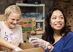 Pitt students Mariel McMarlin (left) and Andrea Agas load fresh fruit into boxes for distribution.