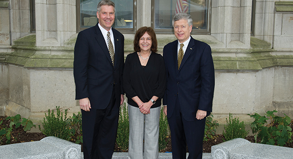 Chancellor Emeritus Mark A. Nordenberg (right) and his wife, Nikki Pirillo Nordenberg, stand by two benches that were gifts to them from Pitt’s University Senate and the Staff Association Council. The benches surround a stone patio, which carries an inscription noting the couple’s dedication and service to to the University. Chancellor Emertitus Nordenberg stepped down Aug. 1 after serving 19 years as Pitt’s CEO. The Nordenbergs share the moment with Chancellor Patrick Gallagher (left).