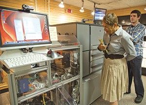 Pitt Professor Emerita of English Toi Derricote inspects the University Store's Espresso Book Machine, with print coordinator Greg Sciulli in background.