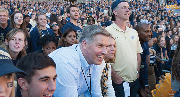Chancellor Patrick Gallagher and his wife, Karen, get caught up in the excitement of the Panthers’ Oct. 10 Homecoming victory against the Virginia Cavaliers at Heinz Field. Standing with the Gallaghers in the student section, known as the “Panther Pitt,” is Jamie Dixon, head coach of the University’s men’s basketball team. (Photo by Mike Drazdzinski/Pitt CIDDE)