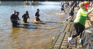 Two dozen University of Pittsburgh police officers helped to raise $2,600 for the Special Olympics of Pennsylvania on Dec. 11 during the organization’s annual “Polar Plunge” event. Members of Pitt’s Swimming and Diving team also participated in the plunge, raising $950 of Pitt’s $2,600 total for the event. Most of the University’s police officers, organized by Lieutenant Holly Lamb, braved the cold Allegheny River: from left, Lieutenant Dave Basile, Sergeant Dan Papale, Officer Heather Camp, and Officer Cory Rogers emerge from the river. The event’s host, former Pittsburgh Steeler Lynn Swan, praised the Pitt officers for the stylish fur hats they all wore on dry land to celebrate their underwater feat. The day’s event raised a total of more than $260,000 for the Special Olympics, twice the amount raised last year.  Credit: Timothy Delaney