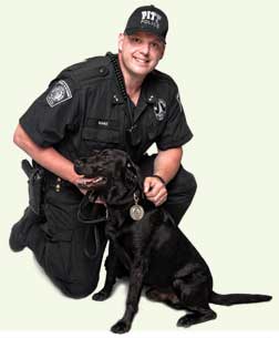 The University has launched a new program, Pitt’s People for Pets, to help local families who, because of tough economic times, are unable to feed their beloved pets. During June and July, Pitt will participate in Animal Friends’ Chow Wagon, which provides pet food to area food banks to ensure that pets and their families can remain together. Pitt Police Department Officer Riggs (below, four legs, wearing leash) has agreed to serve as the Pitt drive’s honorary chair; he poses with his partner, Officer David Nanz, for a publicity photo. Pitt sponsors are Office of the Chancellor, Office of Community Relations, Department of Public Safety, and the University Library System. Online monetary donations can be made by visiting <a href=