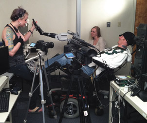 Study participant Tim Hemmes (right) reaches out to his girlfriend, Katie Schaffer (left), using a brain-controlled prosthetic arm. Also pictured is research team member Jennifer L. Collinger.