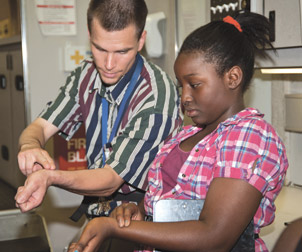 MOBILE LAB FIELD TRIP Youth from the Pitt School of Education’s five-week P.A.C.K. Camp (Physical Activity Camp for Kids) participated in hands-on activities about fitness during a July 6 visit to The Mobile Lab—a self-contained, traveling laboratory that allows students to use current, high-end equipment to perform laboratory investigations. Here, Nathan Rockcastle explains to Zoe Vongtau how to locate her radial pulse so she could obtain a resting (before exercise) reading and an active (after exercise) reading. Rockcastle is an administrative supervisor in the lab of Judy Cameron, a Pitt professor of psychiatry and a senior scientist in the Oregon National Primate Research Center at Oregon Health and Science University. The Mobile Lab is a project of the Pitt Department of Biological Sciences, the University of Pittsburgh Clinical and Translational Sciences Institute, The Pittsburgh Life Sciences Greenhouse, The Lyceum Group, Thermo Fisher, and the Pittsburgh Tissue Engineering Initiative.