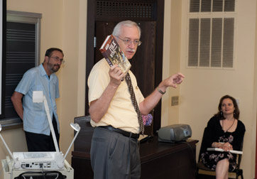 USING MUSIC AS A TEACHING TOOL:  What’s the best way to teach an 11-year-old about important events in U. S. history without his eyes glazing over? Mix American music into the curriculum, according to Deane Root (center), codirector of Pitt’s Voices Across Time institute that was held on the Pittsburgh campus June 27-July 29. Root is a professor of music and director and Fletcher Hodges Jr. Curator of the Center for American Music at Pitt. Twenty-three teachers from across the country gathered with music historians and musicians to learn how to weave songs into classroom material. “Music is a medium kids relate to,” said Norm Cohen (left), a Portland, Oregon-based author and historian with expertise in railroad folk songs. “They don’t think of it as an educational tool.” Institute administrator Kathryn Miller Haines is seated on the right.